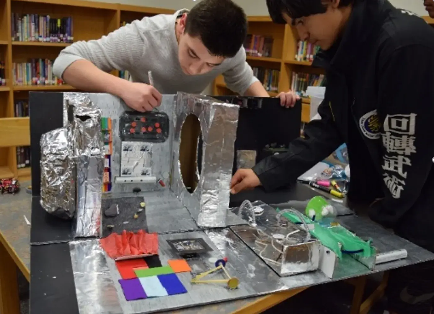Two students building their space colony model in a school library