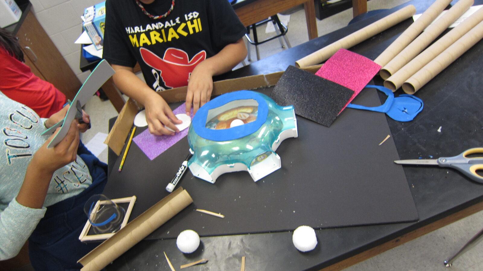 Students building a colony model from recycled materials