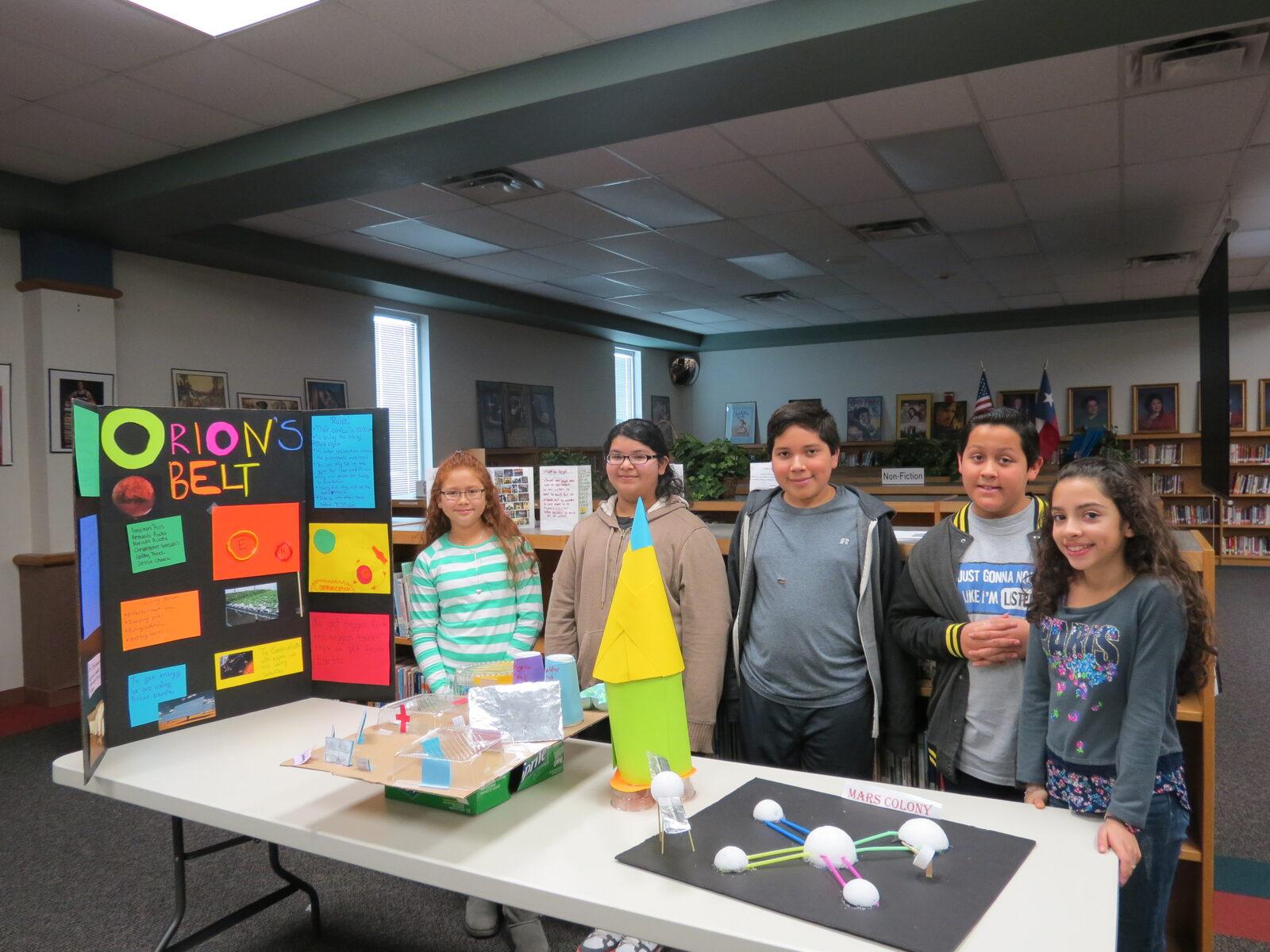 A student team proudly presenting the space-colony project they researched, designed, and built